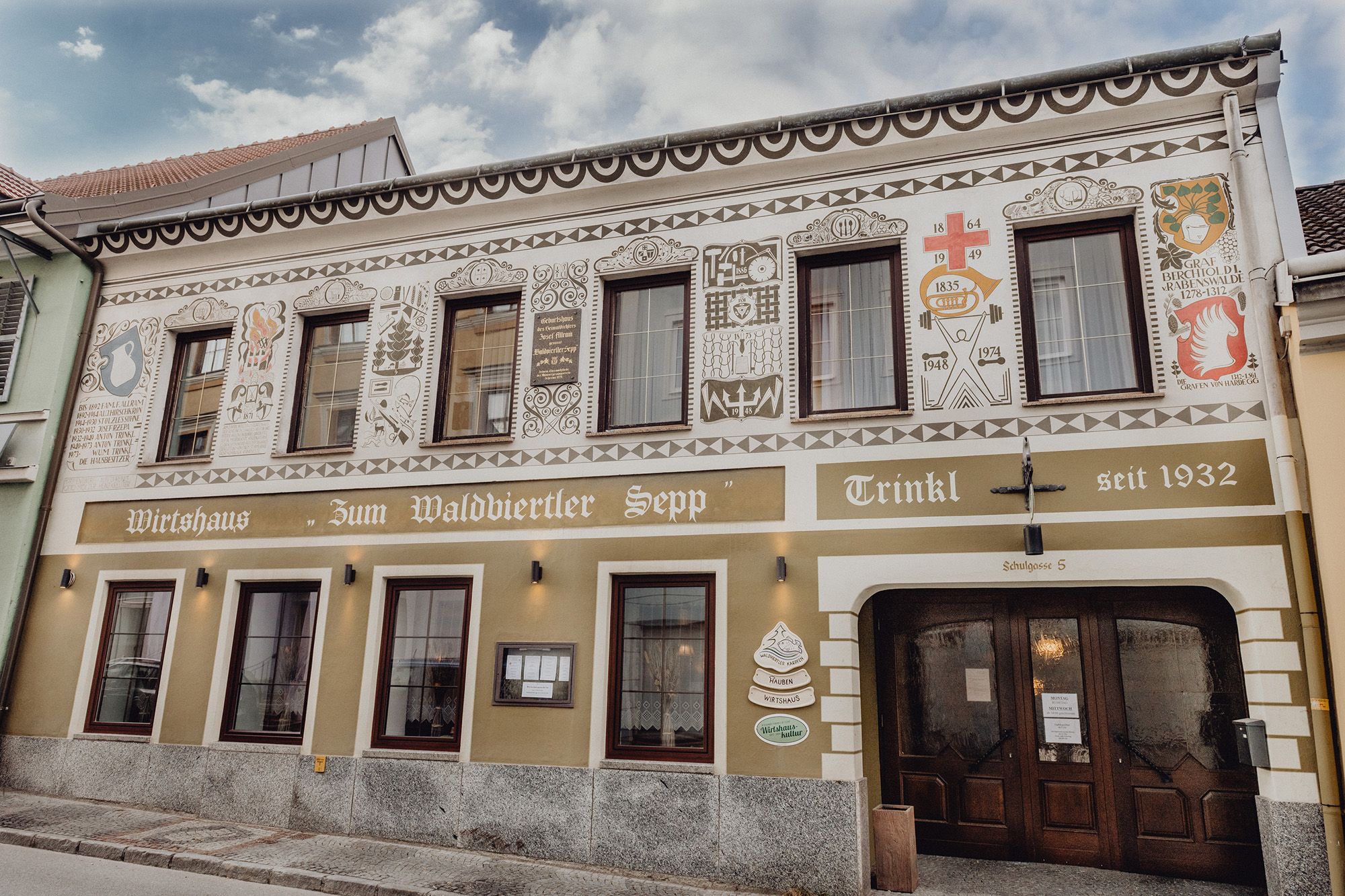 Egy hagyományos fogadó homlokzata díszítő festményekkel és a "Zum Waldviertler Sepp" felirattal Schremsben.