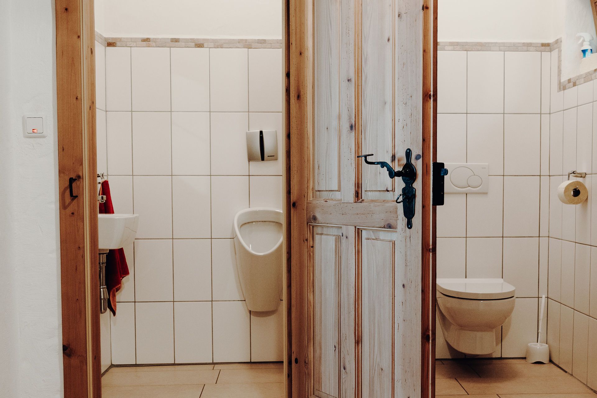 Két faajtós mellékhelyiség, balra egy piszoár és egy mosdó, jobbra egy WC.