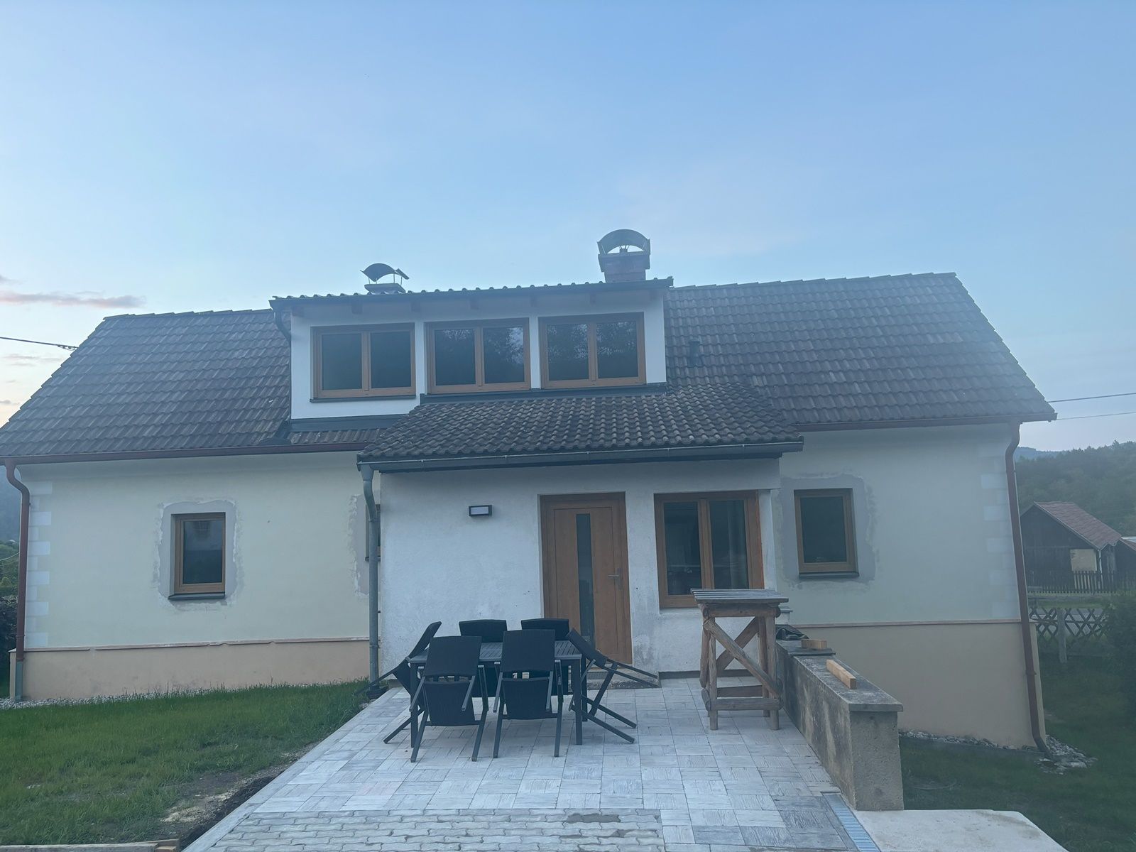 Kétszintes, tetőzsindellyel és terasszal ellátott, pázsittal és vidéki környezettel körülvett nyaraló.