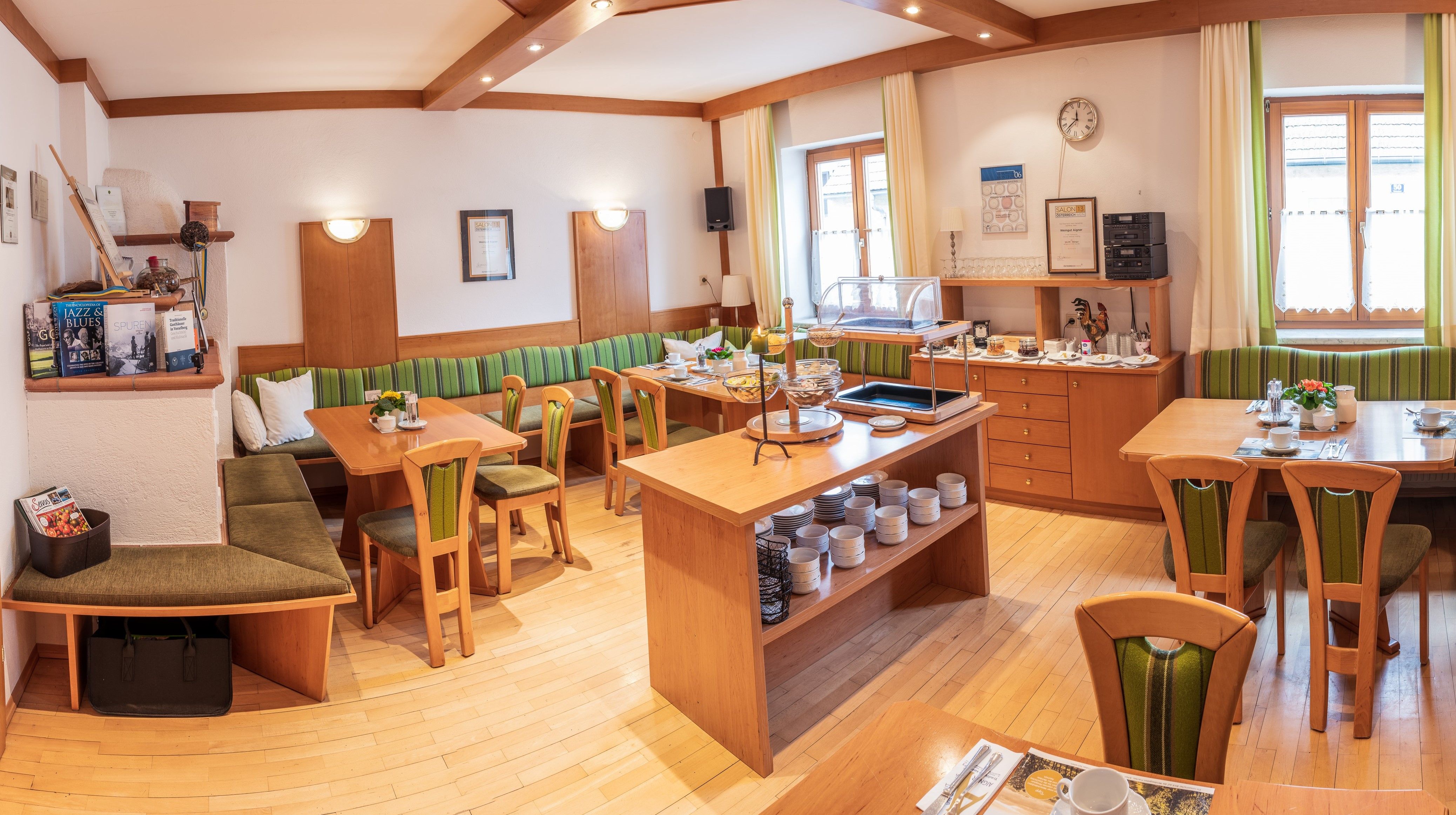 Hangulatos reggelizőterem fabútorokkal, terített asztalokkal és büfével.