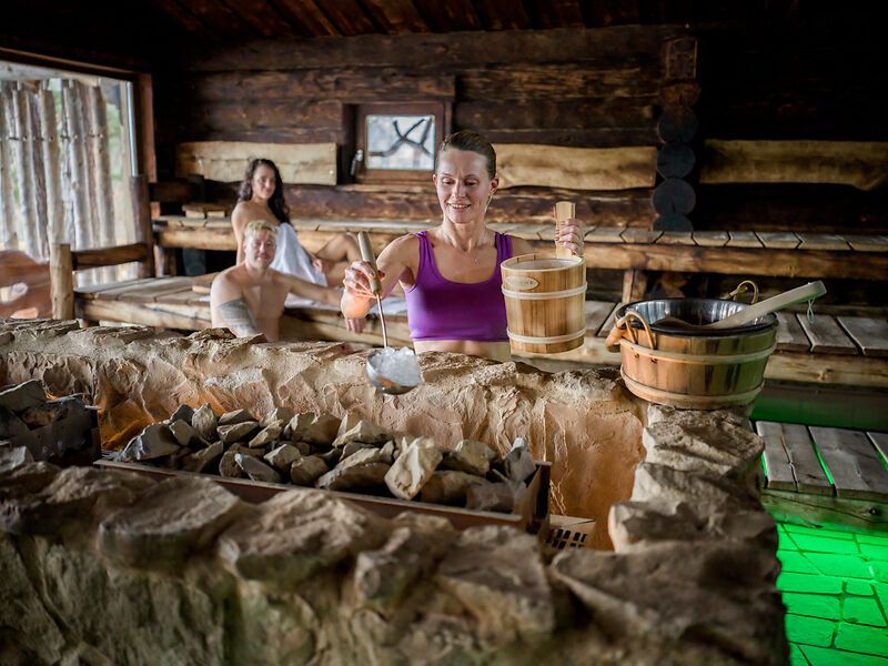 Egy személy vizet önt a szaunában lévő forró kövekre.
