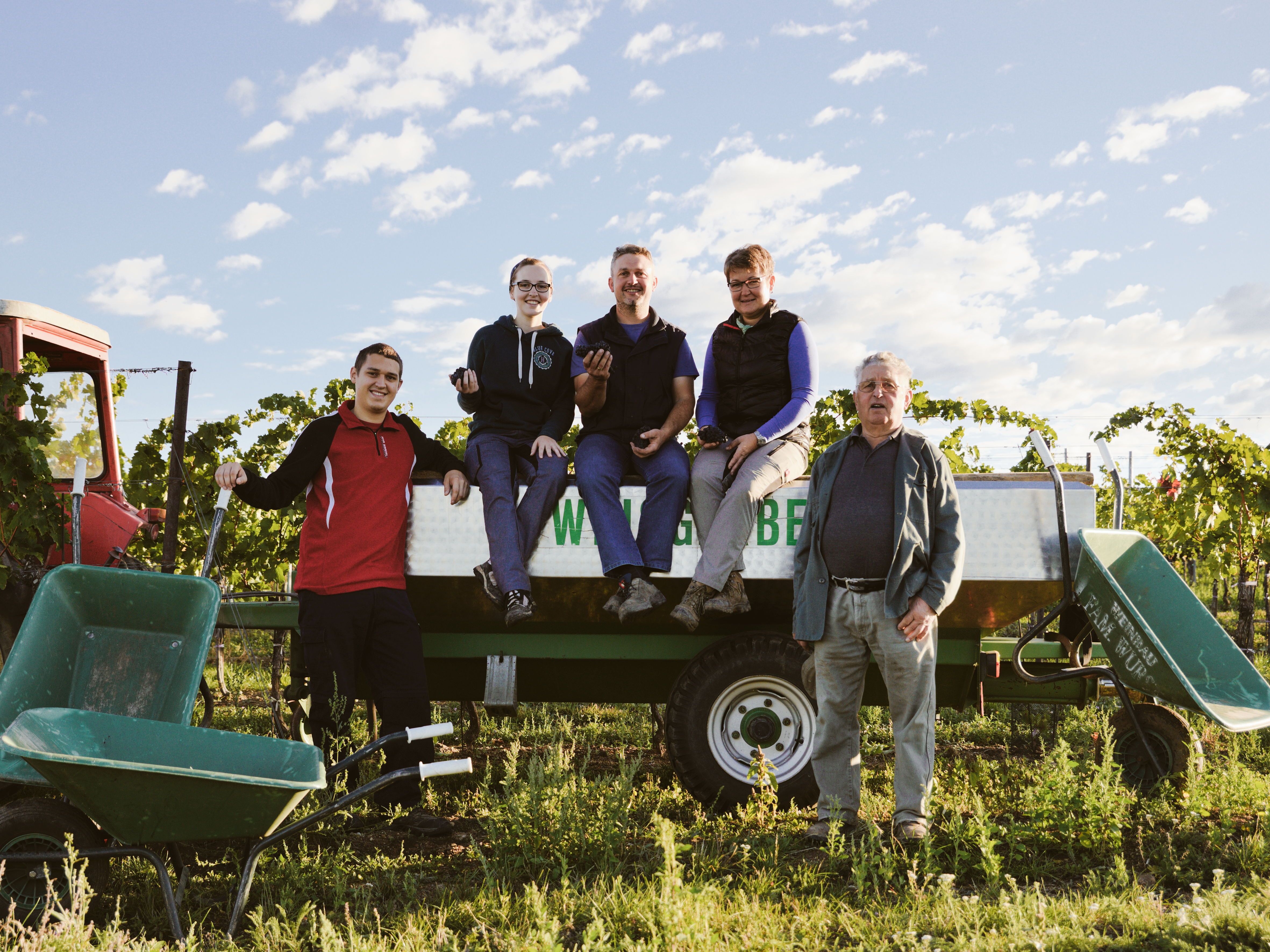 Egy család pózol egy traktor utánfutóján egy szőlőben.